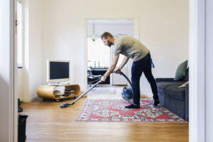man vacuuming a carpets with pets